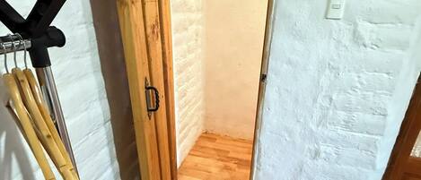 Ein schmaler Flur mit einer Holztür, die in einen Raum mit Holzboden führt.