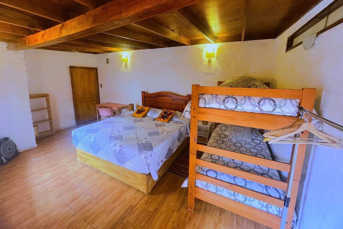 A bedroom with a wooden bed, a small desk, a chair, and a wooden wardrobe.