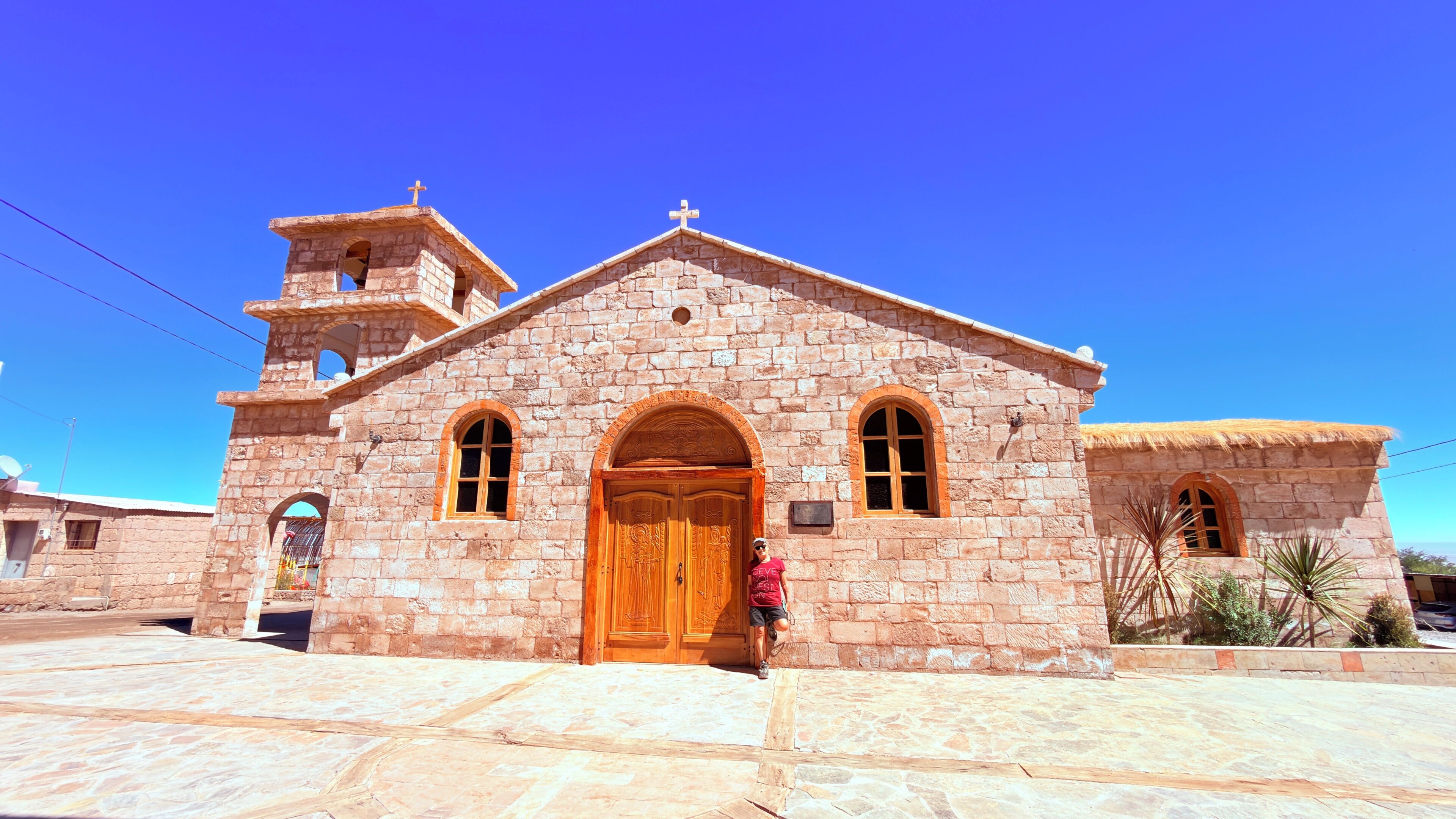 Une église en pierre avec une porte en bois, des fenêtres en arc de cercle et un clocher.