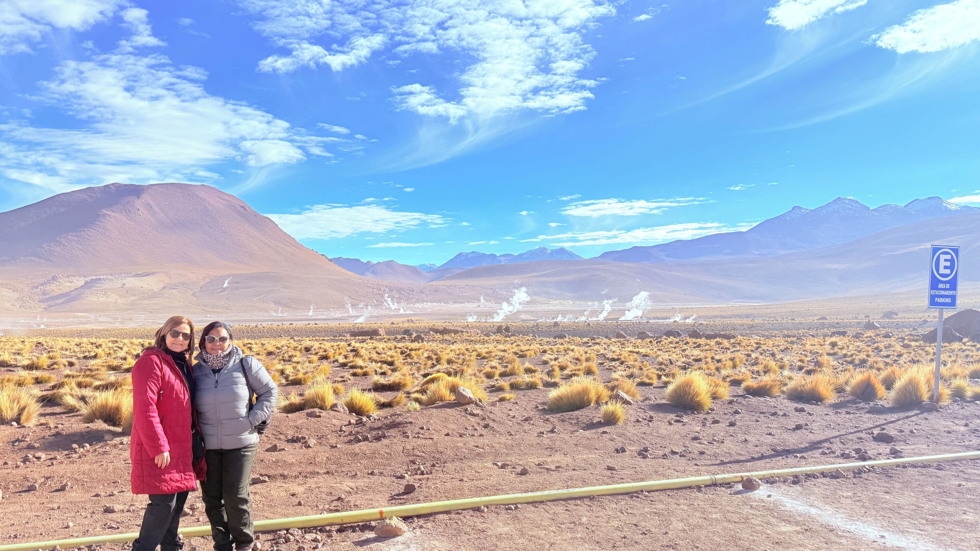 A desert landscape with mountains in the background, a clear sky, and a sign indicating a parking area.