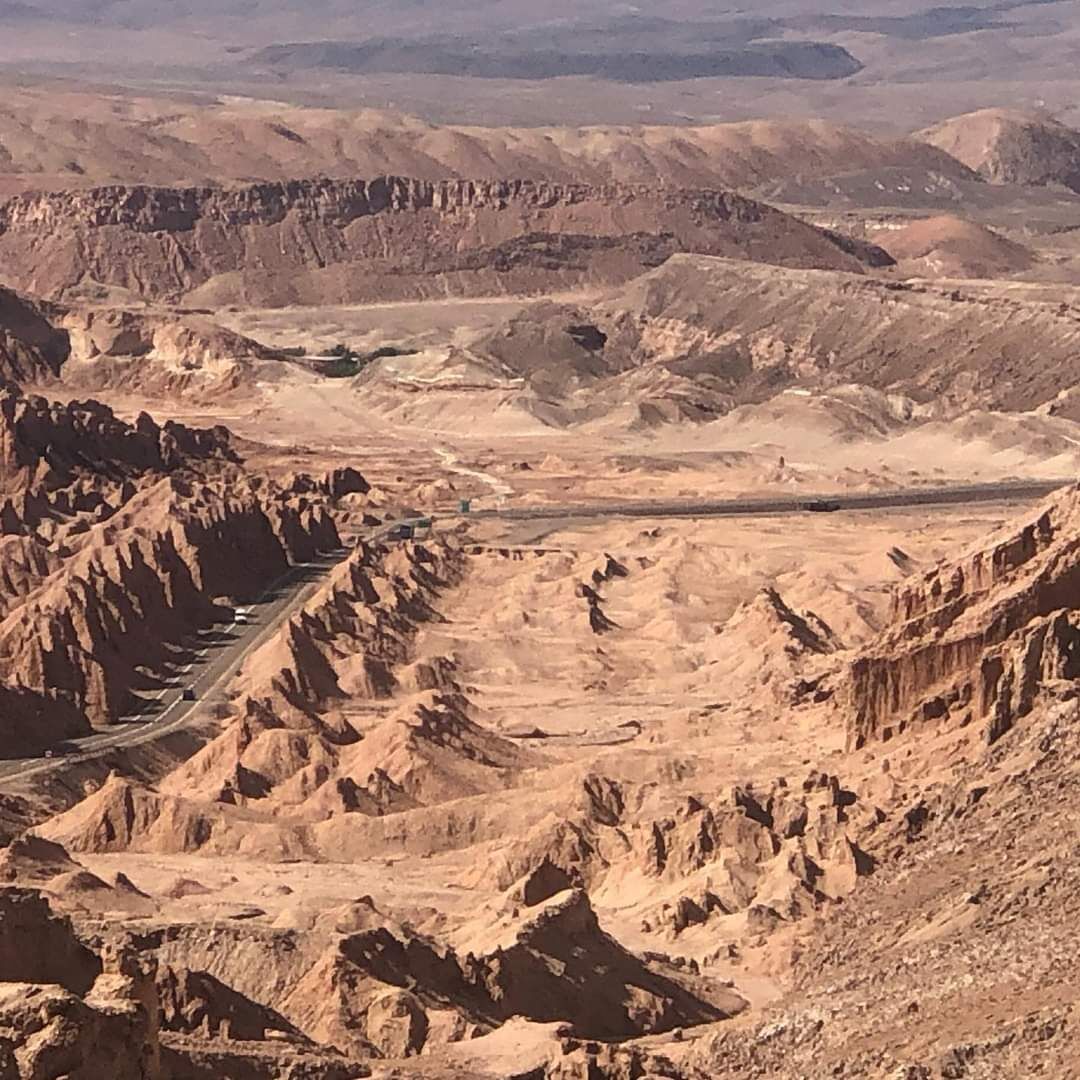 Paisaje desértico con terreno accidentado y una carretera que lo atraviesa.