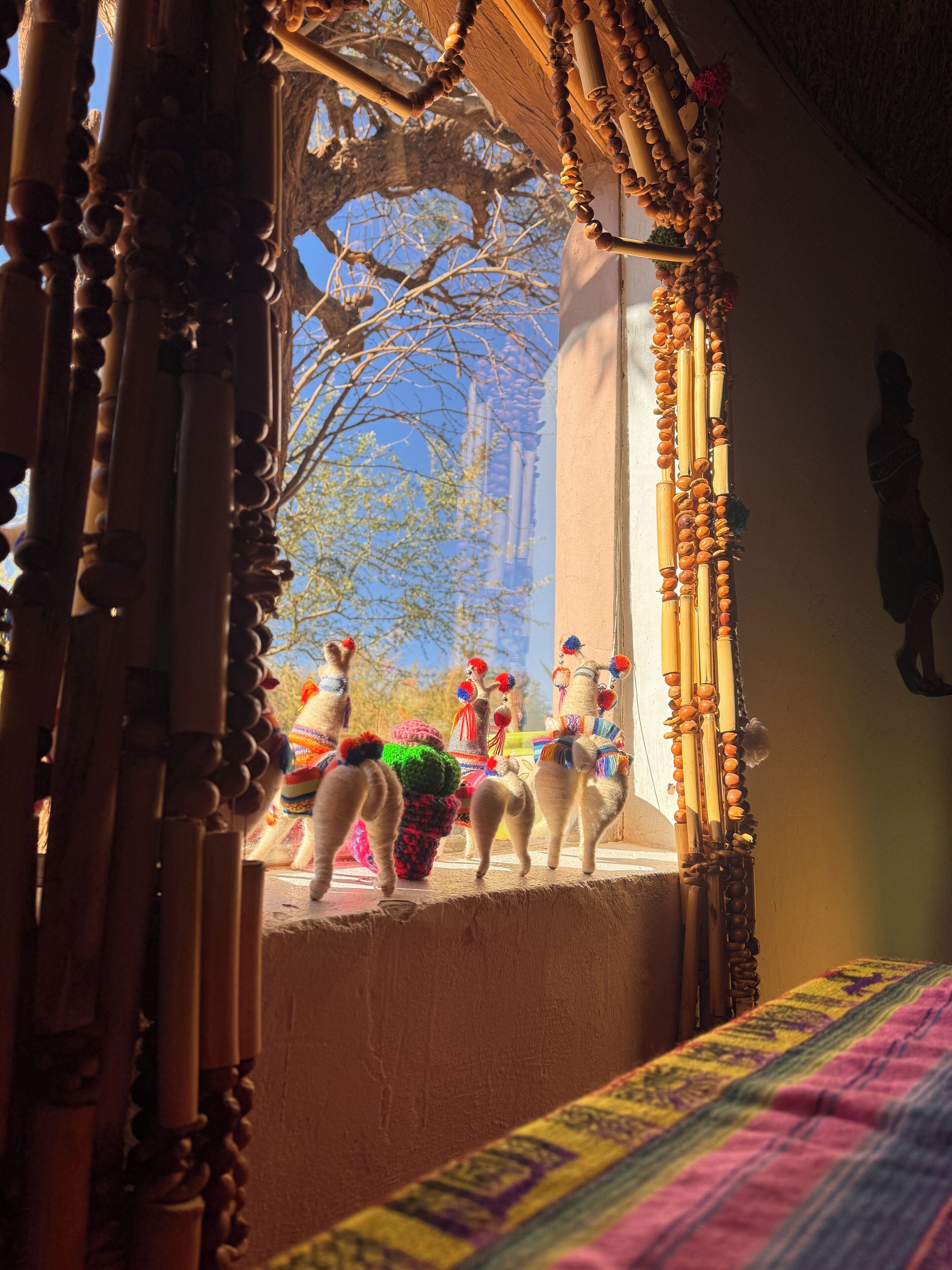 A room with a view of a tree and a window with decorative beads.