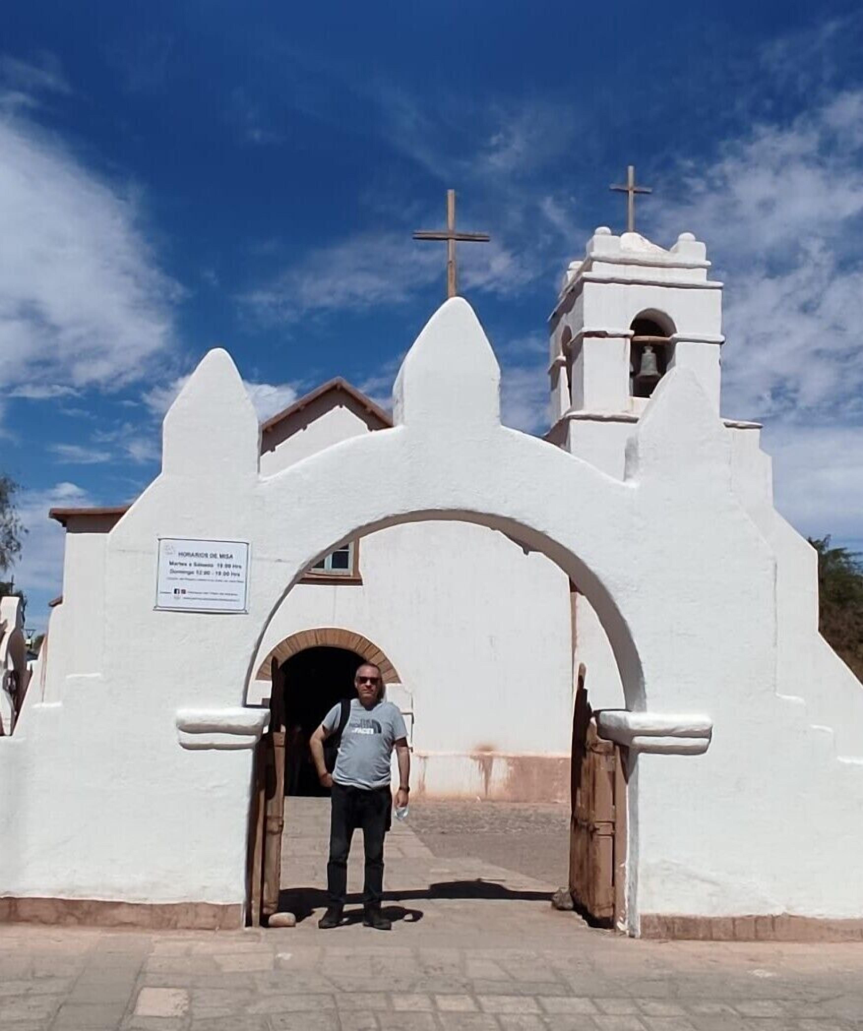 A white church with a bell tower and a cross on top.