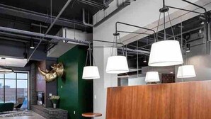 A modern interior with wooden seating, round tables, and pendant lighting.