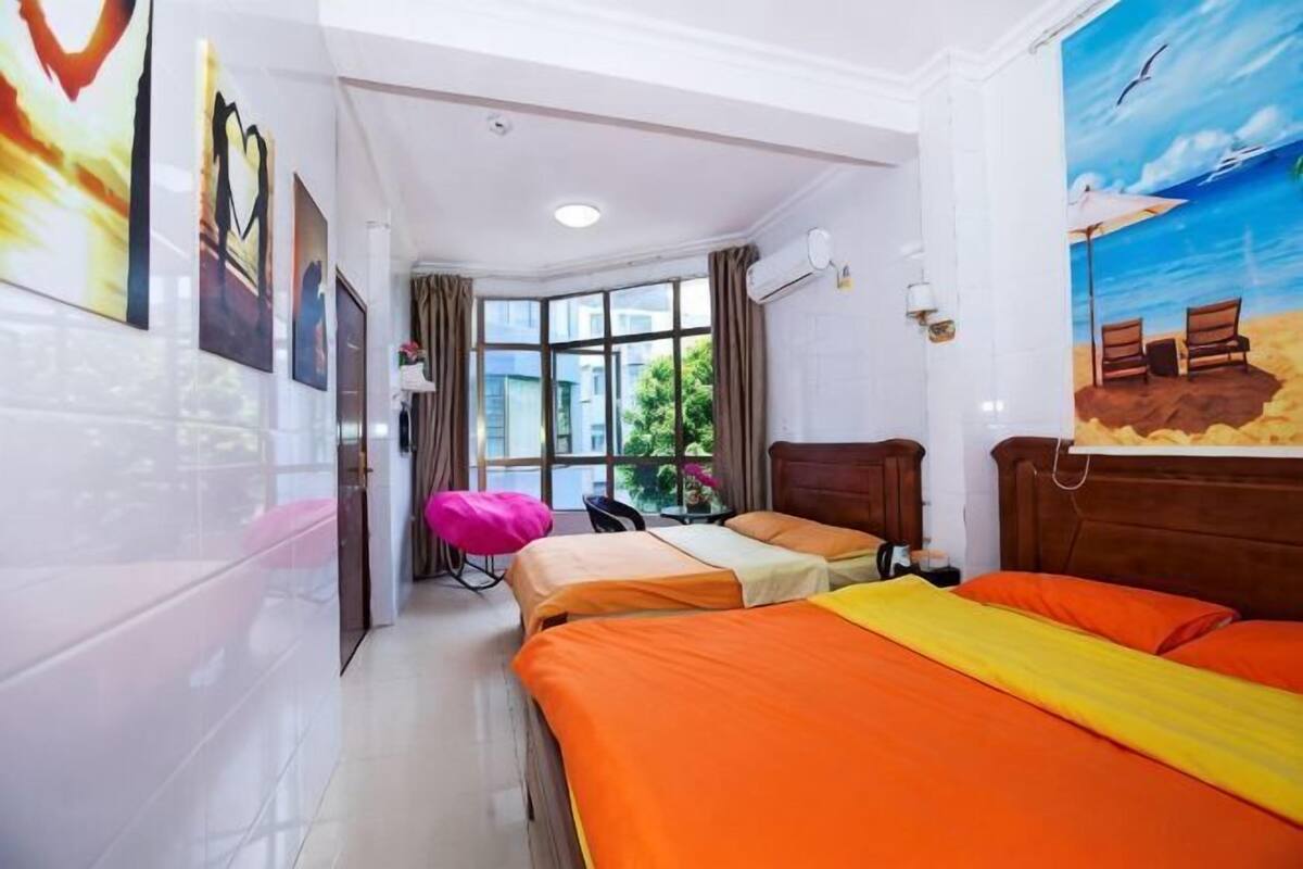 Ein Hotelzimmer mit zwei Betten, einem Fenster mit Blick, einem Strandbild und einem Sessel.