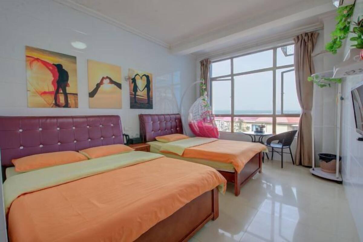 Ein Hotelzimmer mit zwei Betten, einem Balkon und Blick sowie Bildern an der Wand.