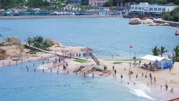 A coastal area with a rocky beach, a pier, and a flag.