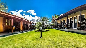 A courtyard with a central palm tree, surrounded by buildings with wooden facades and lattice windows. - Vila Jacaré (Brotas)