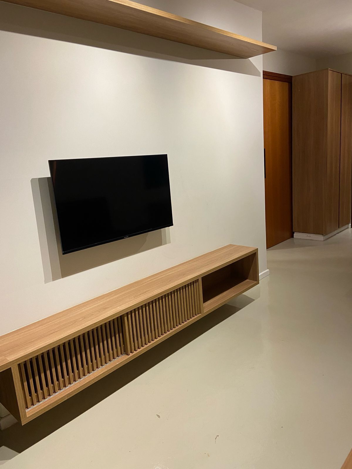 A modern living room with a mounted flat-screen TV, wooden console, and built-in cabinets.