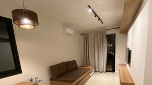 A modern living room with a wooden coffee table, a brown sofa, a hanging light fixture, and a television mounted on the wall. - Vila Jacaré (Brotas)