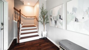 Una escalera de madera con barandilla, una planta en maceta y arte abstracto en la pared.