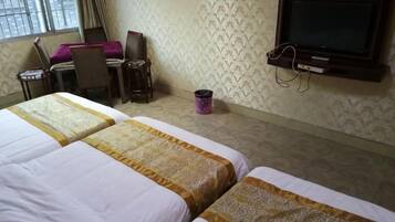 A hotel room with two beds, a desk, a chair, a television, and a window.
