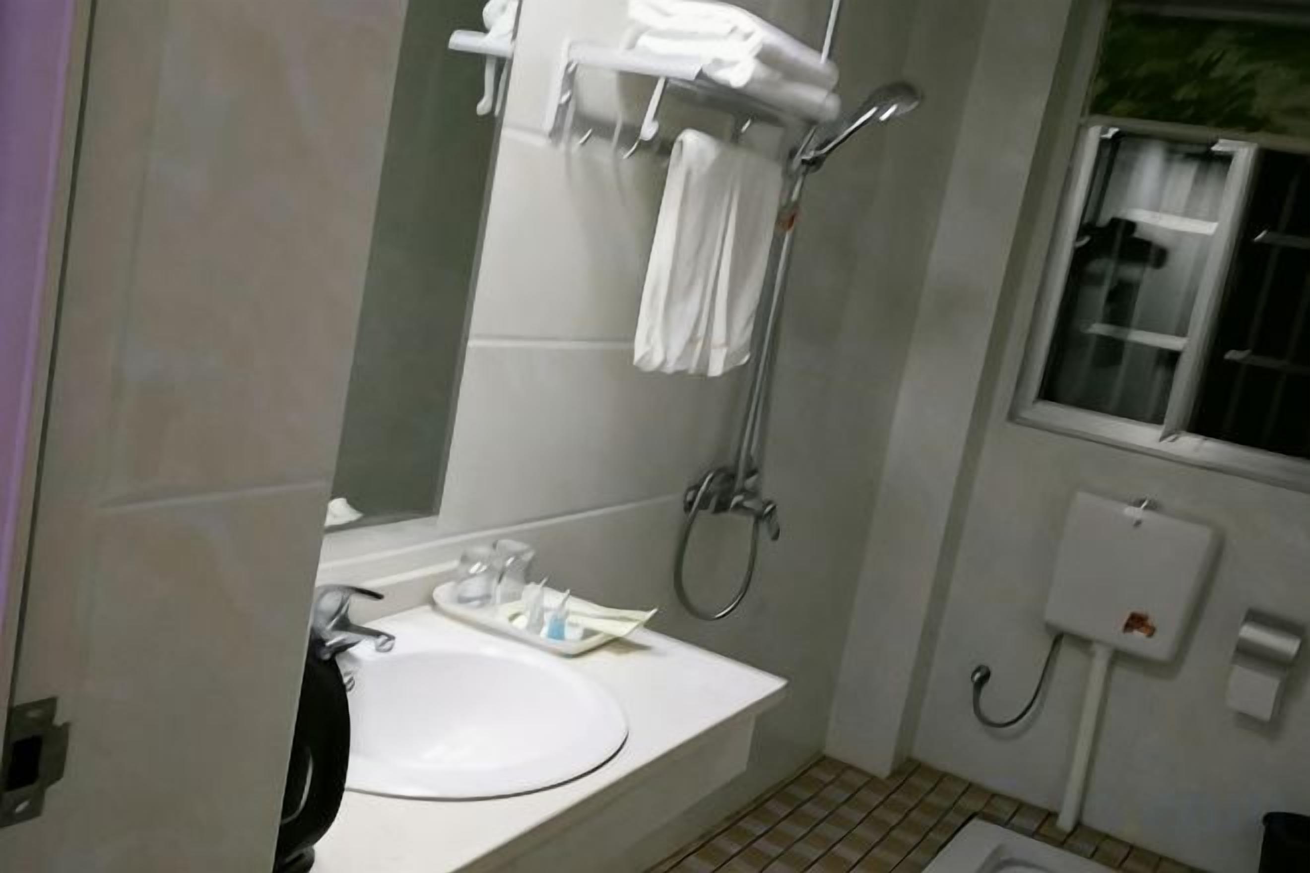 A bathroom with a sink, mirror, towel rack, shower, and a window.