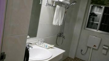 A bathroom with a sink, mirror, towel rack, shower, and a window.
