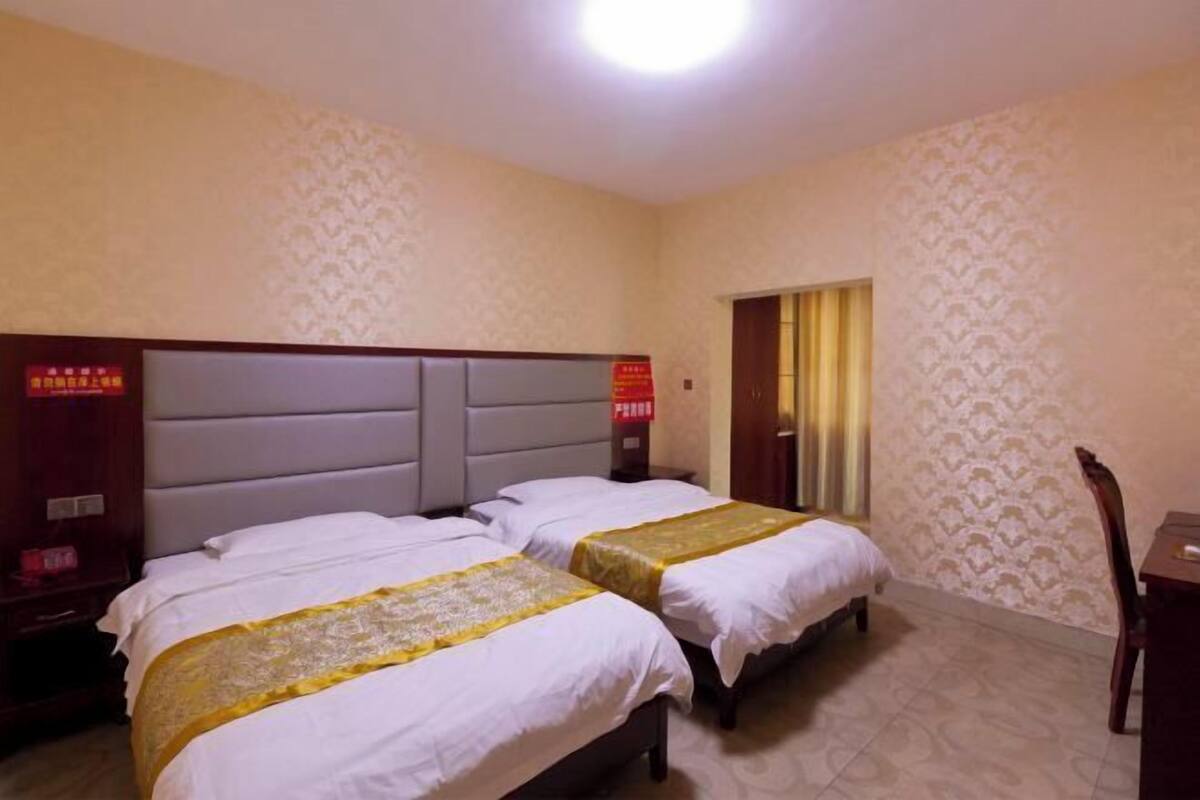 A hotel room with two beds, a wooden headboard, a nightstand, a desk, and a chair.
