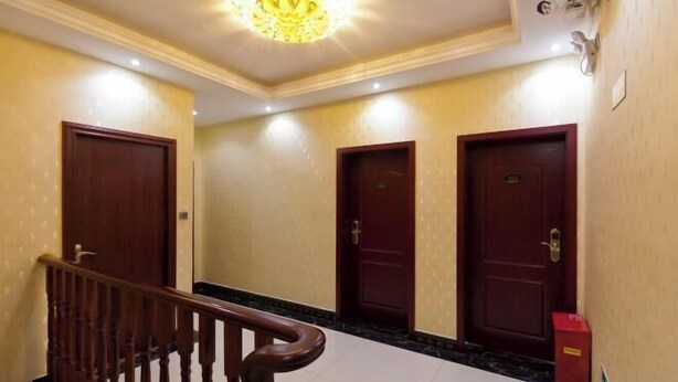 Un pasillo de hotel con tres puertas de madera, suelo de mármol y una escalera de madera con barandilla.