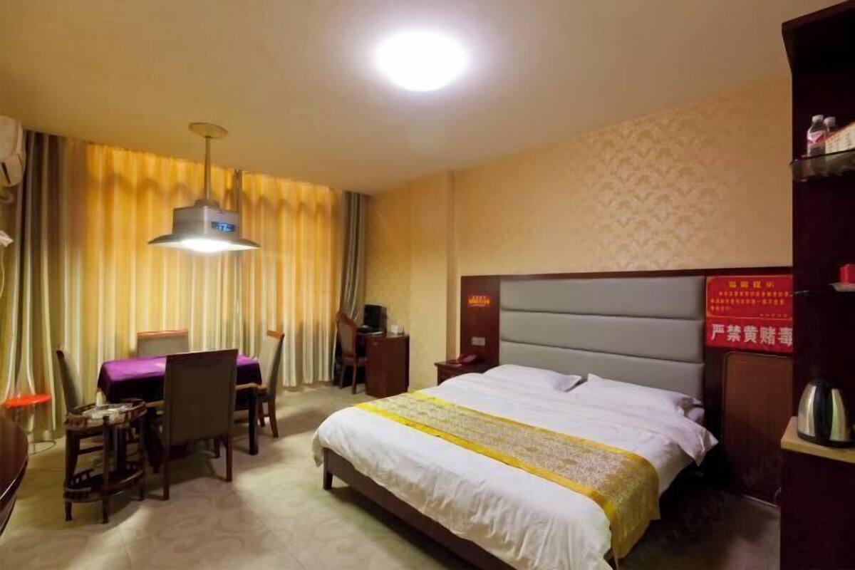A hotel room with a bed, a desk with a chair, a lamp, and a nightstand.