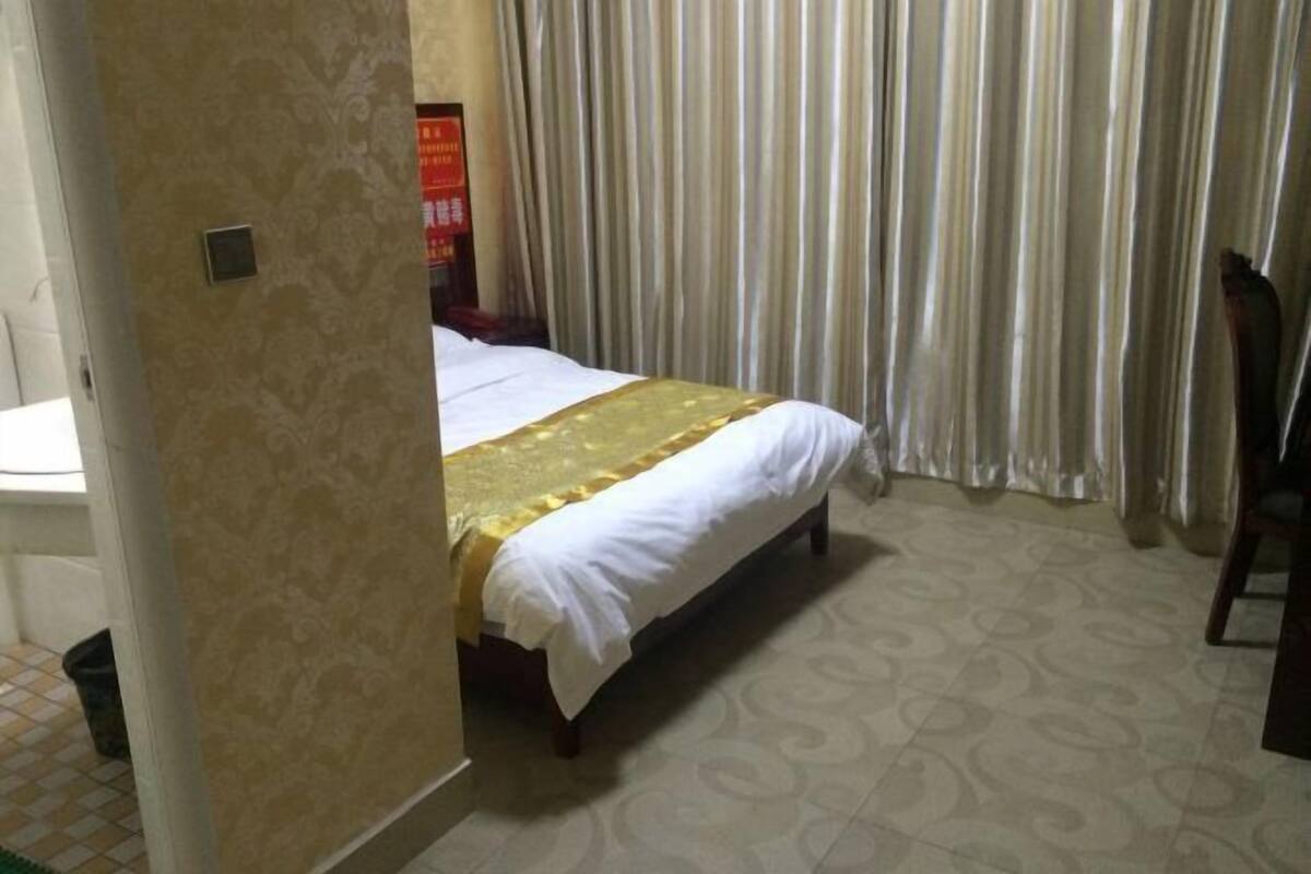A hotel room with a bed, a chair, and a curtain.