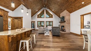 A spacious kitchen with a wooden ceiling, a large island, and a fireplace.