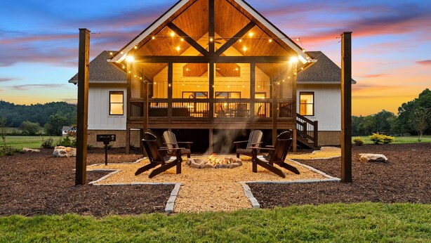 A large, two-story log cabin with a covered deck and outdoor seating area.