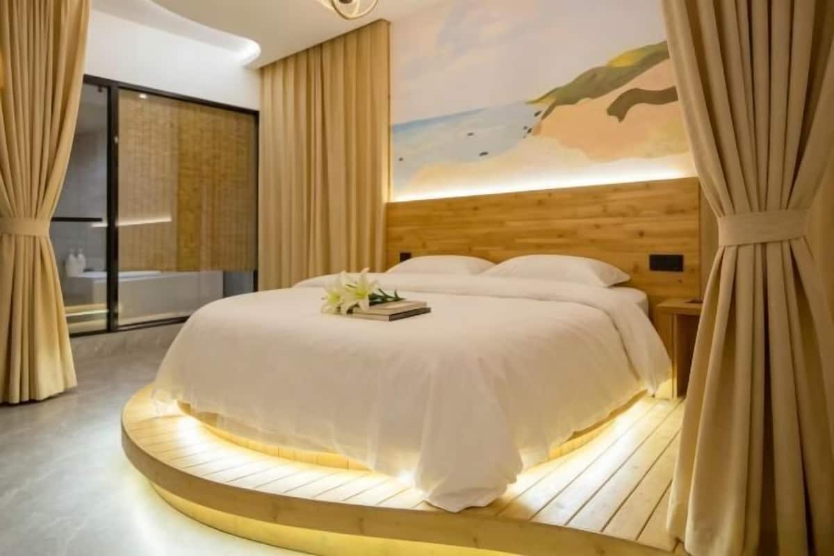 Une chambre à coucher avec un lit rond, une tête de lit en bois et une fresque murale.