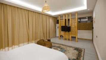 Un dormitorio moderno con una cama grande, una lámpara de techo, un televisor y un panel decorativo en la pared.