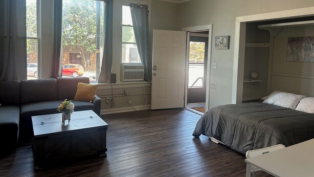 A room with a bed, a sofa, a small table, and a ceiling fan.