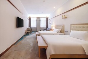 Habitación de hotel con dos camas, un escritorio, un televisor y una ventana con cortinas.