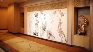 A hallway with traditional Chinese artwork on the walls, a patterned carpet, and a golden abstract sculpture. - Wanli Hotel (Chengdu Head Office) (Chengdu)