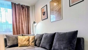 Un salon moderne avec un canapé d’angle gris, une lampe sur pied et un vase rempli de fleurs posé sur une table basse.