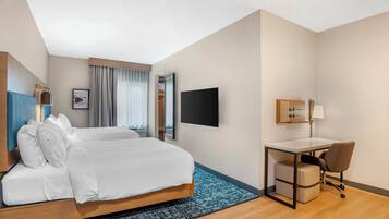 A hotel room with a bed, a desk, a chair, a TV, and a wardrobe.