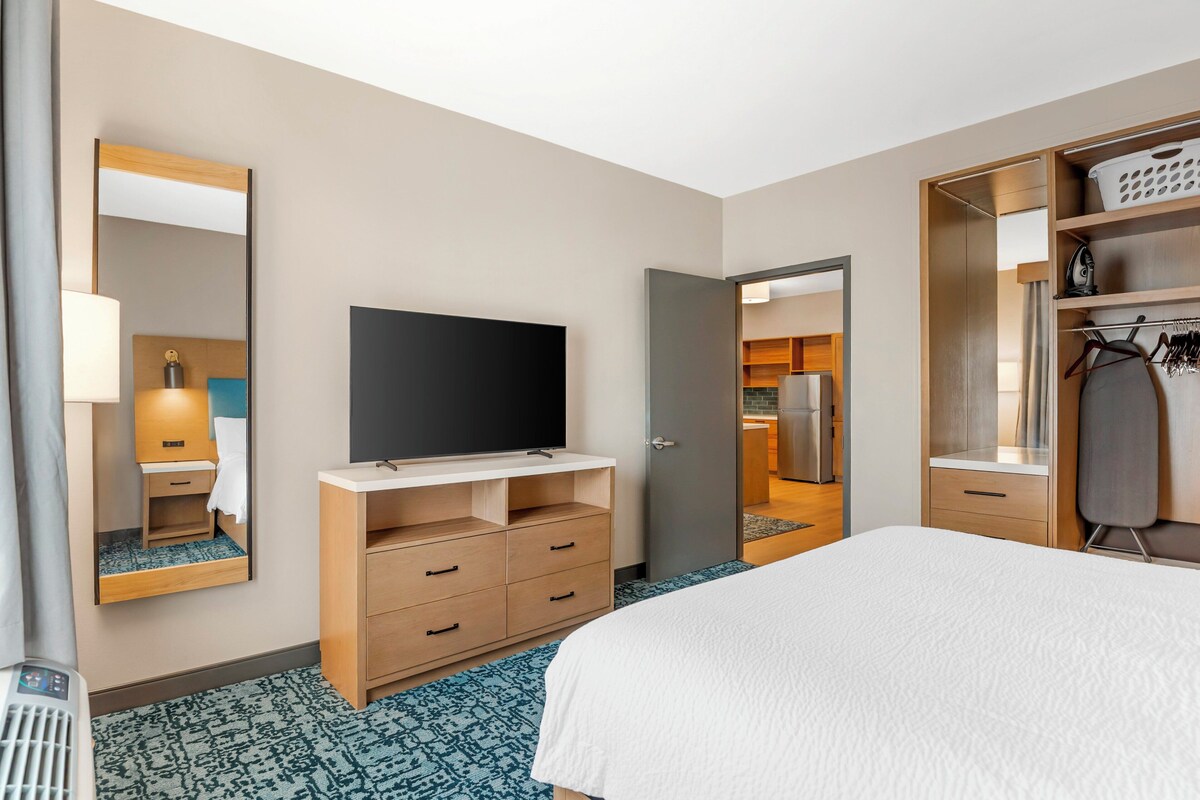Een hotelkamer met een bed, een televisie, een kledingkast en een badkamer, zichtbaar door een open deur.