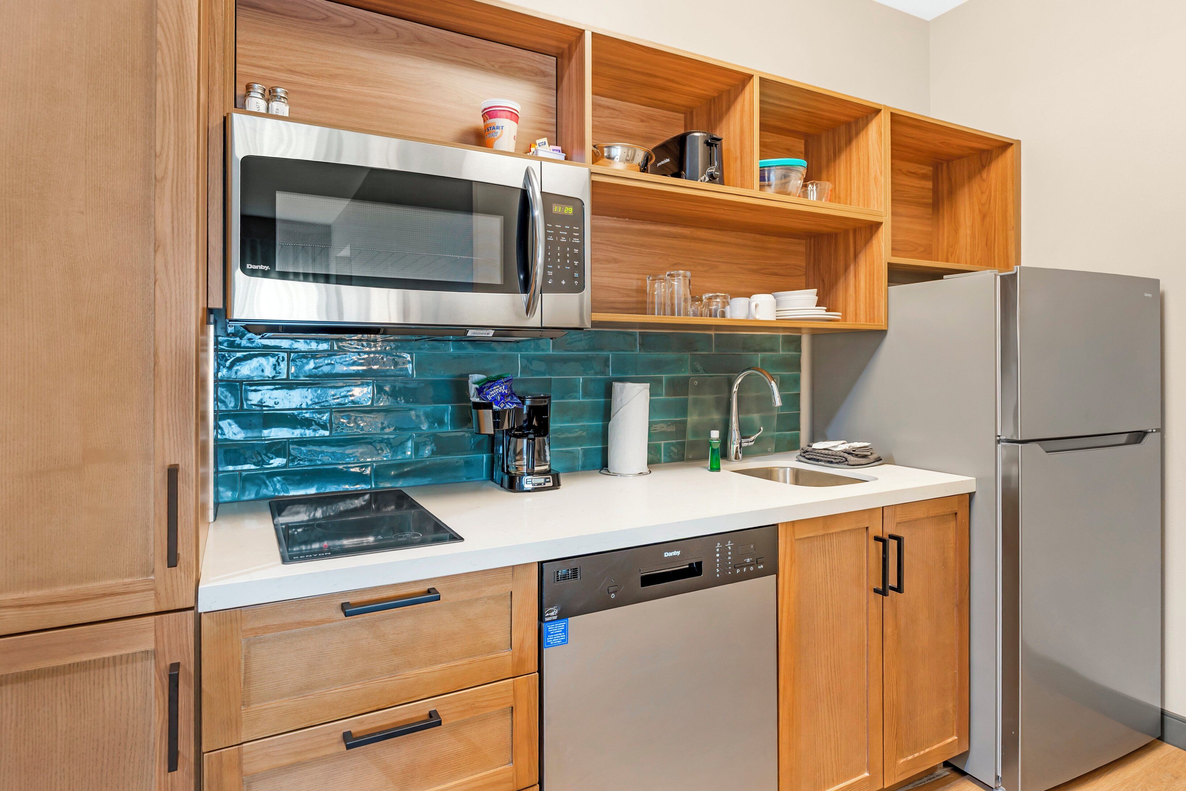 A modern kitchen with wooden cabinets, a stainless steel microwave, a dishwasher, and a refrigerator.