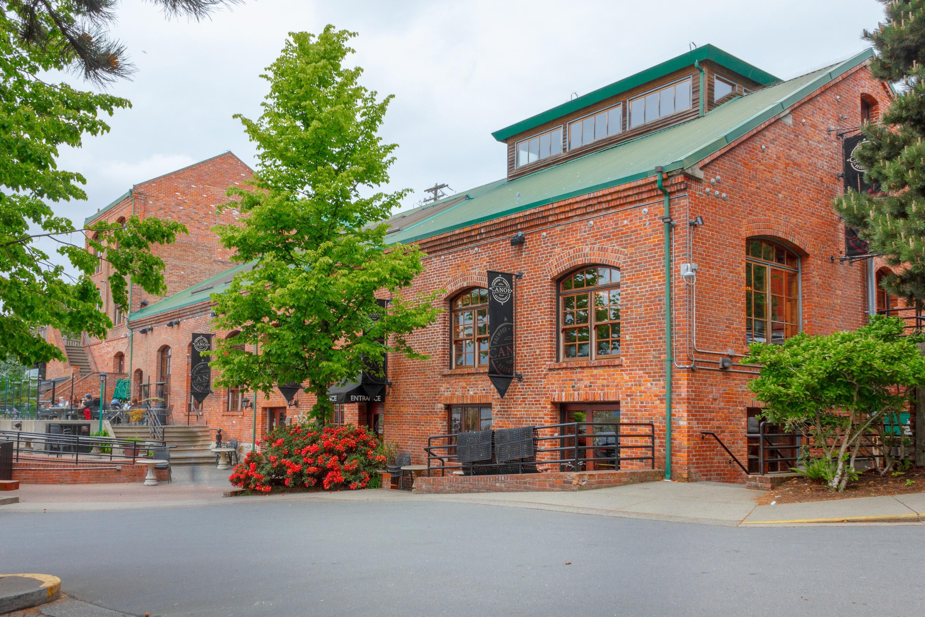 A brick building with a green roof, large windows, and a sign that reads "Entrance."