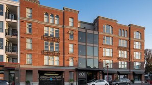 A multi-story building with a brick facade, large windows, and a modern entrance. - Bright Condo in Victoria's Trendy Old Town (Victoria North)