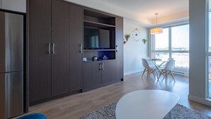 A modern kitchen with dark wooden cabinets, a built-in microwave, and a dining area with a white table and chairs. - Chic Downtown Suite & People-Watching Deck (Victoria Central British Columbia Provincial Government)