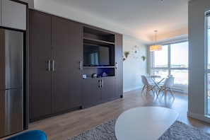 A modern kitchen with dark wooden cabinets, a built-in microwave, and a dining area with a white table and chairs. - Chic Downtown Suite & People-Watching Deck (Victoria Central British Columbia Provincial Government)