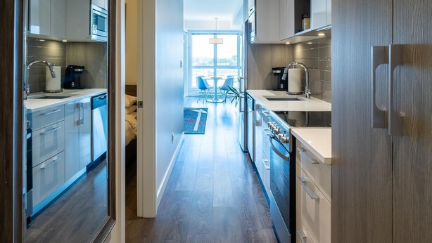 A modern kitchen with wooden cabinets, stainless steel appliances, and a central island. - Panoramic City Views and Modern Style Condo (Victoria Central British Columbia Provincial Government)