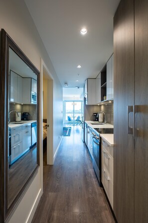 A modern kitchen with wooden cabinets, stainless steel appliances, and a central island. - Panoramic City Views and Modern Style Condo (Victoria Central British Columbia Provincial Government)