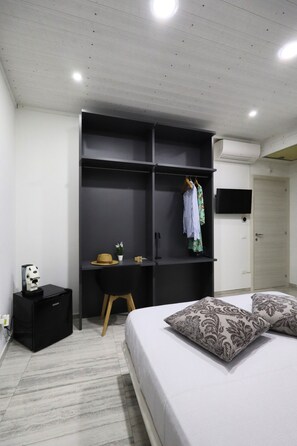 Une chambre à coucher avec un lit, une armoire, un bureau, une chaise, une télévision et une porte.