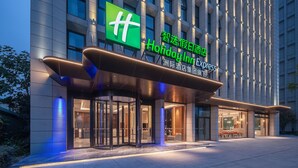 A hotel entrance with a modern design, featuring a prominent green 'Holiday Inn Express' sign and a glass revolving door. - Holiday Inn Express Chengdu Shuangliu Airport by IHG (Chengdu)