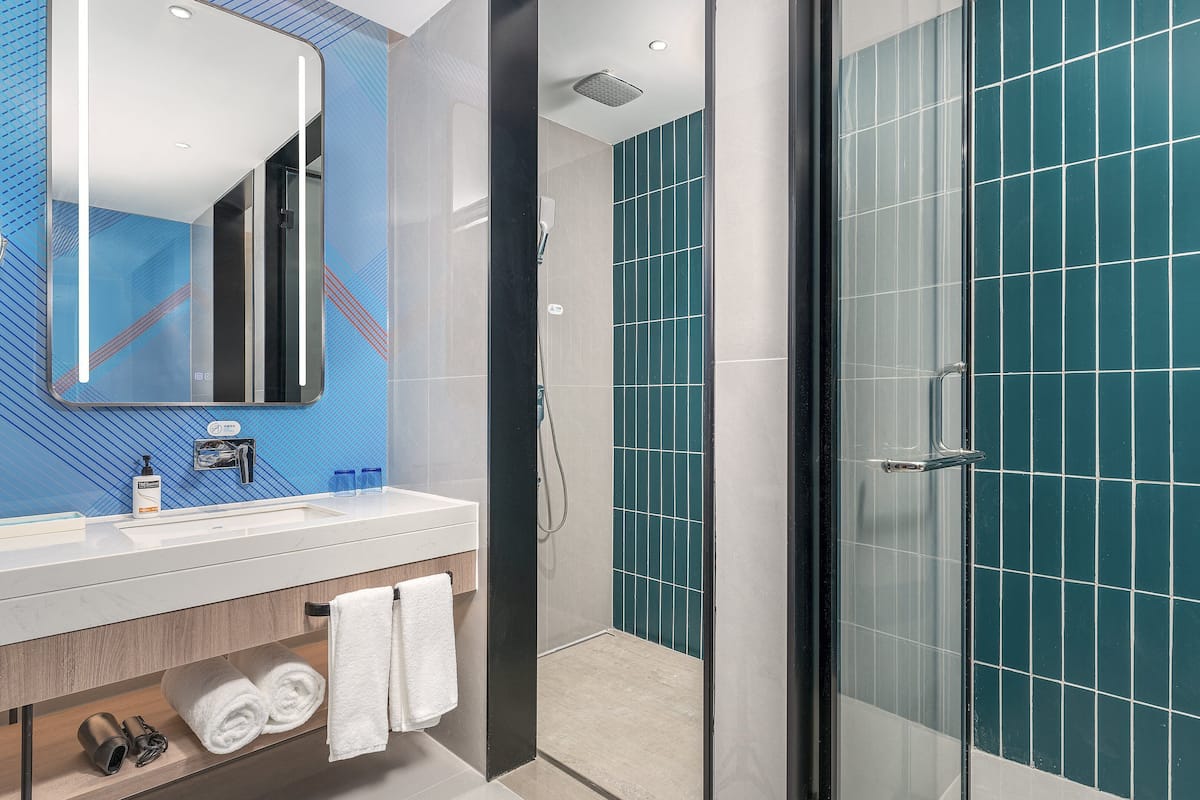 A modern bathroom with a glass shower enclosure, a vanity with a mirror, and a sink.