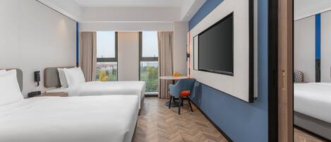 Une chambre d’hôtel avec deux lits, une télévision, un bureau avec une chaise et une fenêtre donnant sur un paysage agréable.