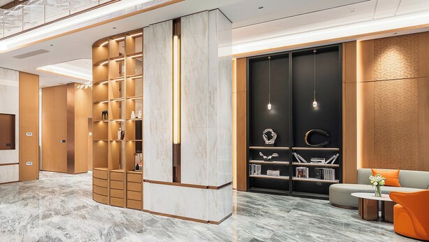 A modern lobby with a marble floor, wooden shelving with decorative items, a black bookshelf with books, and a seating area with orange chairs. - Holiday Inn Express Chengdu Shuangliu Airport by IHG (Chengdu)