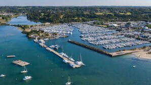An aerial view of a marina with numerous boats docked, surrounded by greenery and a river. - ZEcamping 4 étoiles animé parc aquatique locatif TV 30m2 4 pers (Fouesnant)