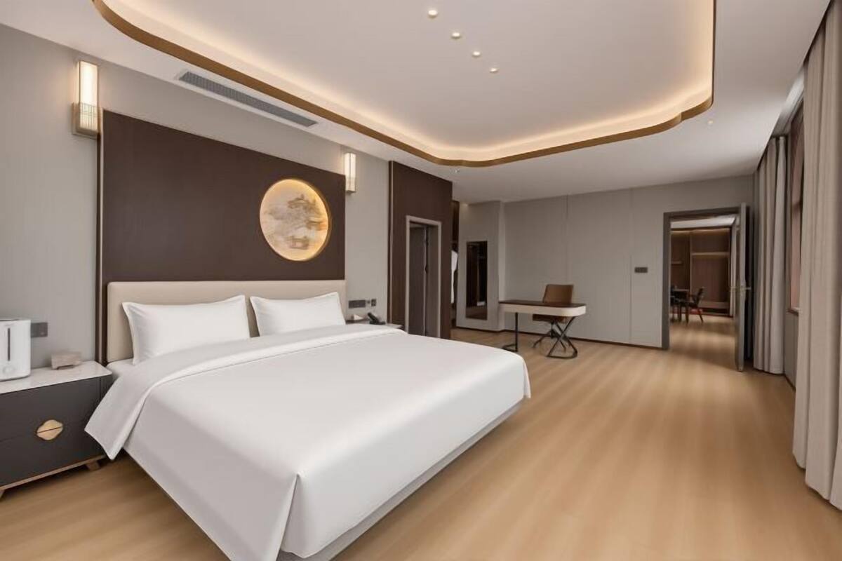 Une chambre d’hôtel moderne dotée d’un grand lit, de tables de chevet, d’un bureau et d’un coin repas.