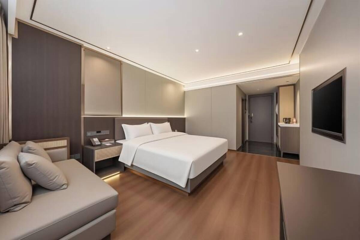 Une chambre d’hôtel moderne équipée d’un lit, d’un canapé, d’un bureau et d’une télévision.