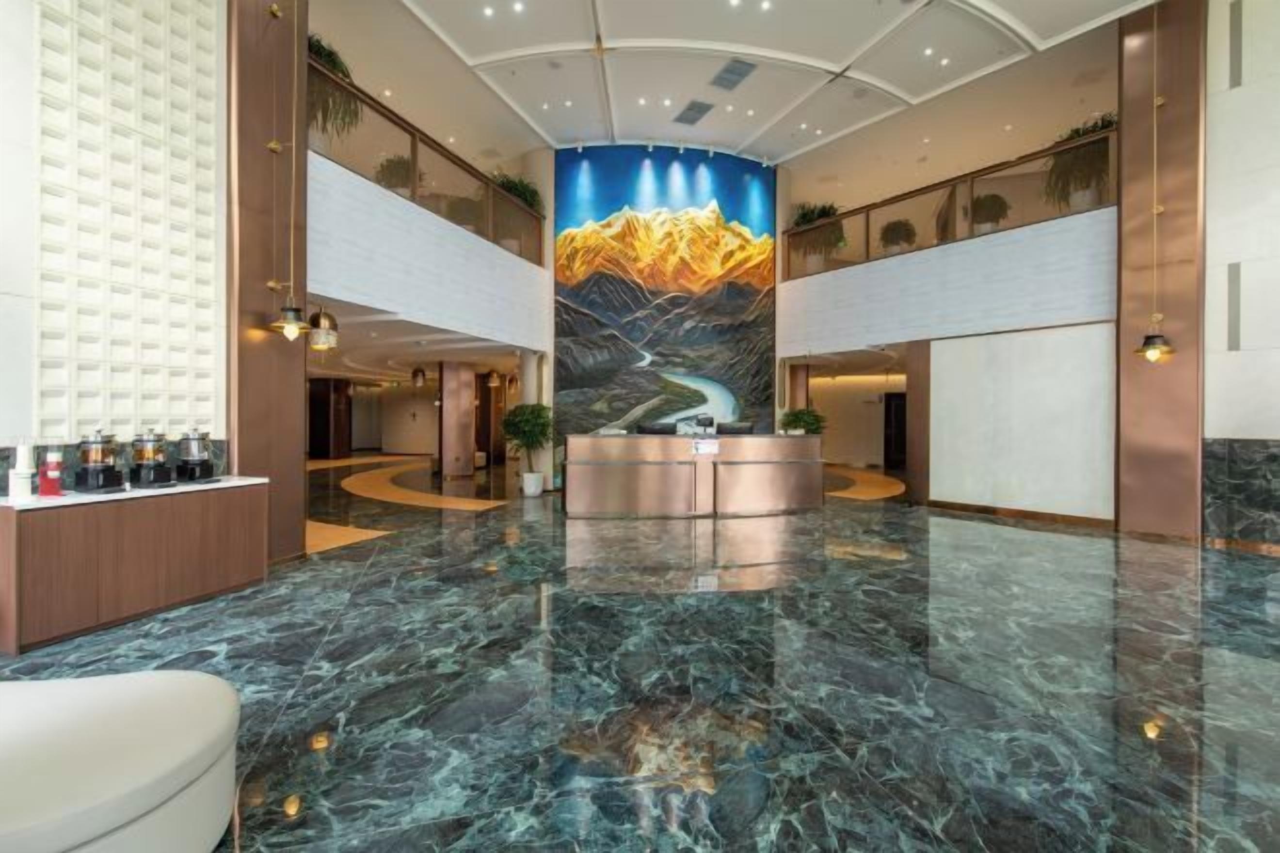 A hotel lobby with a reception desk, marble flooring, and a mural of mountains.