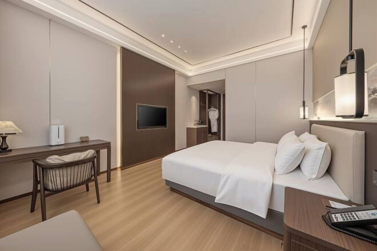 Une chambre d’hôtel moderne équipée d’un lit, d’une table de chevet, d’une lampe et d’un téléviseur.