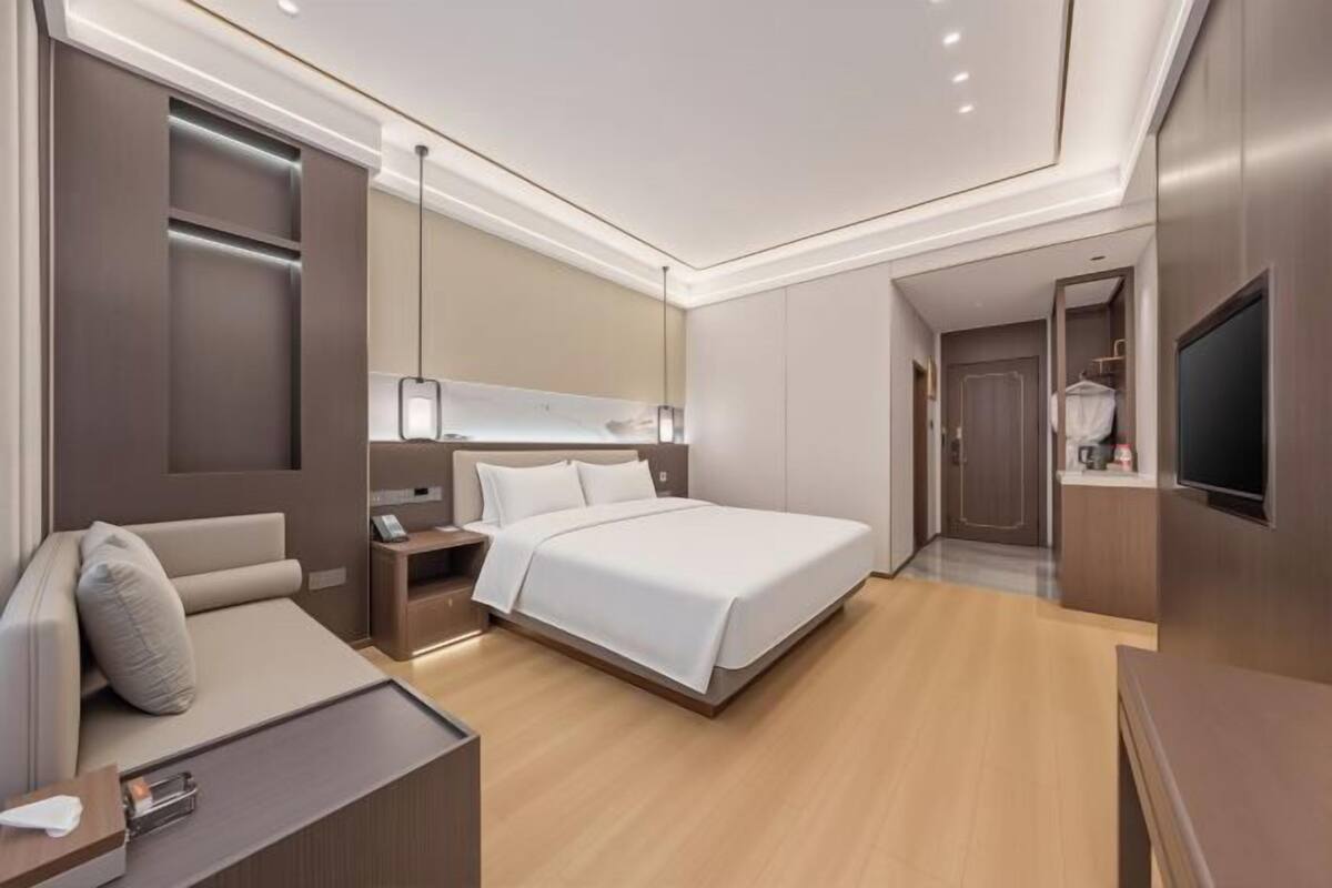 Une chambre d’hôtel moderne équipée d’un lit, d’une table de chevet, d’une lampe et d’un téléviseur.